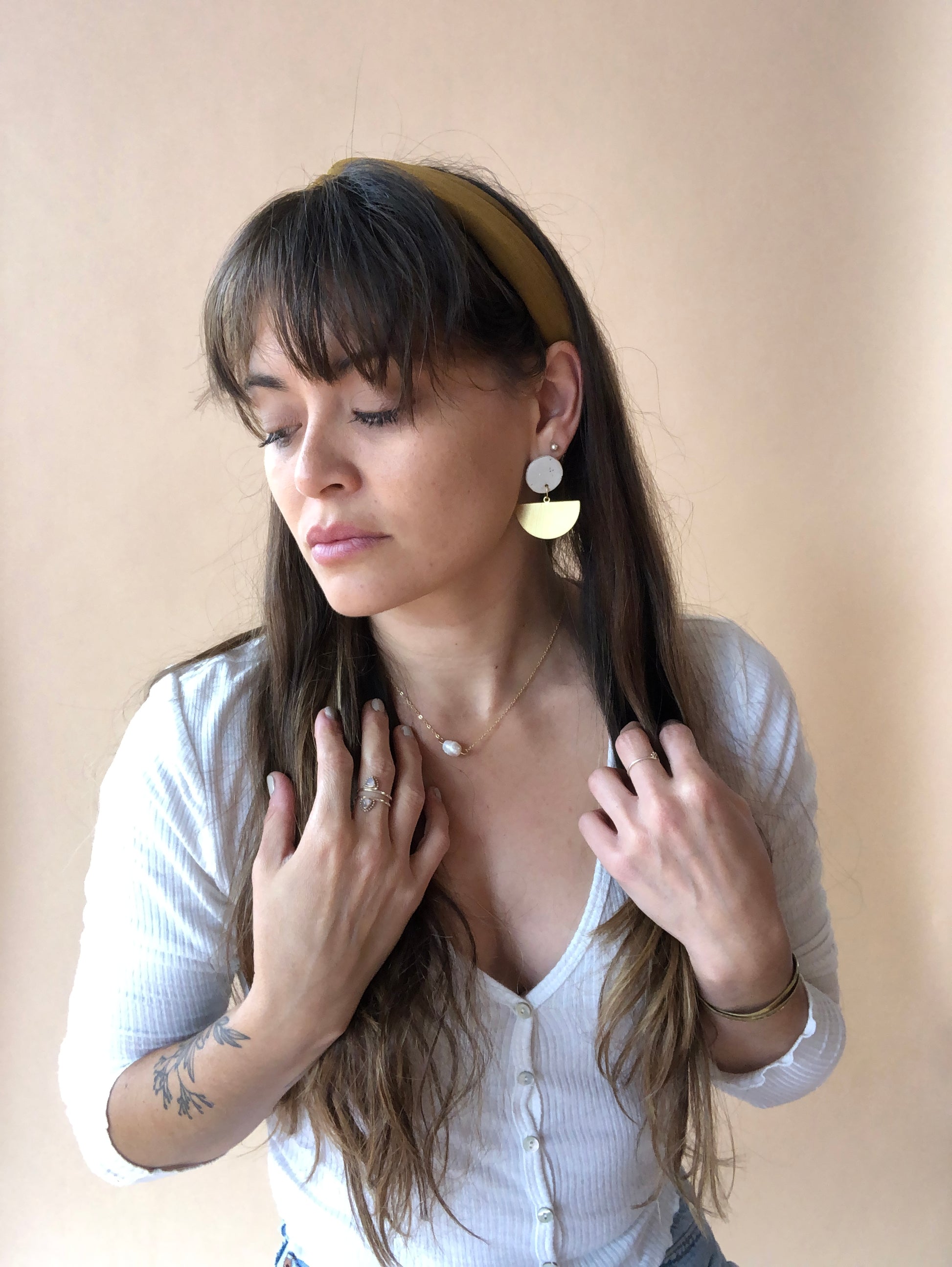 model wearing ceramic and brass earrings resembling a boat