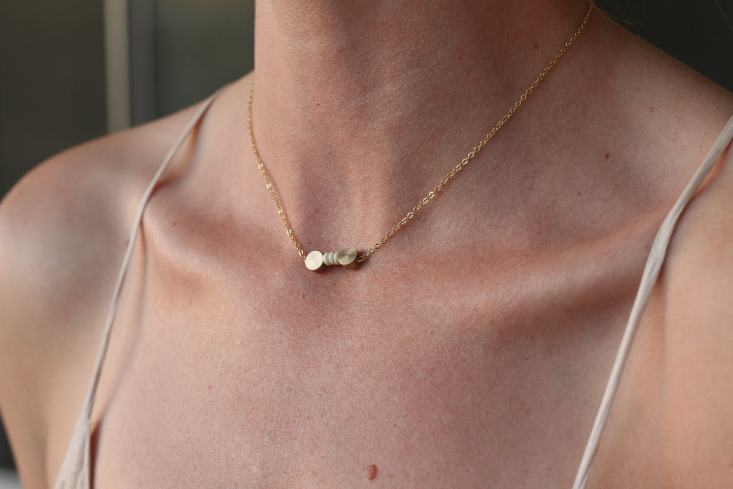 a dainty stone and brass necklace on a gold or brass chain