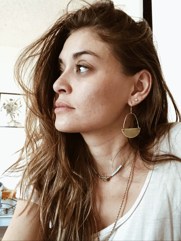 model wears brass half moon shaped earrings