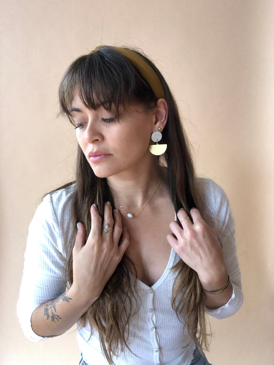 model wearing ceramic and brass earrings resembling a boat